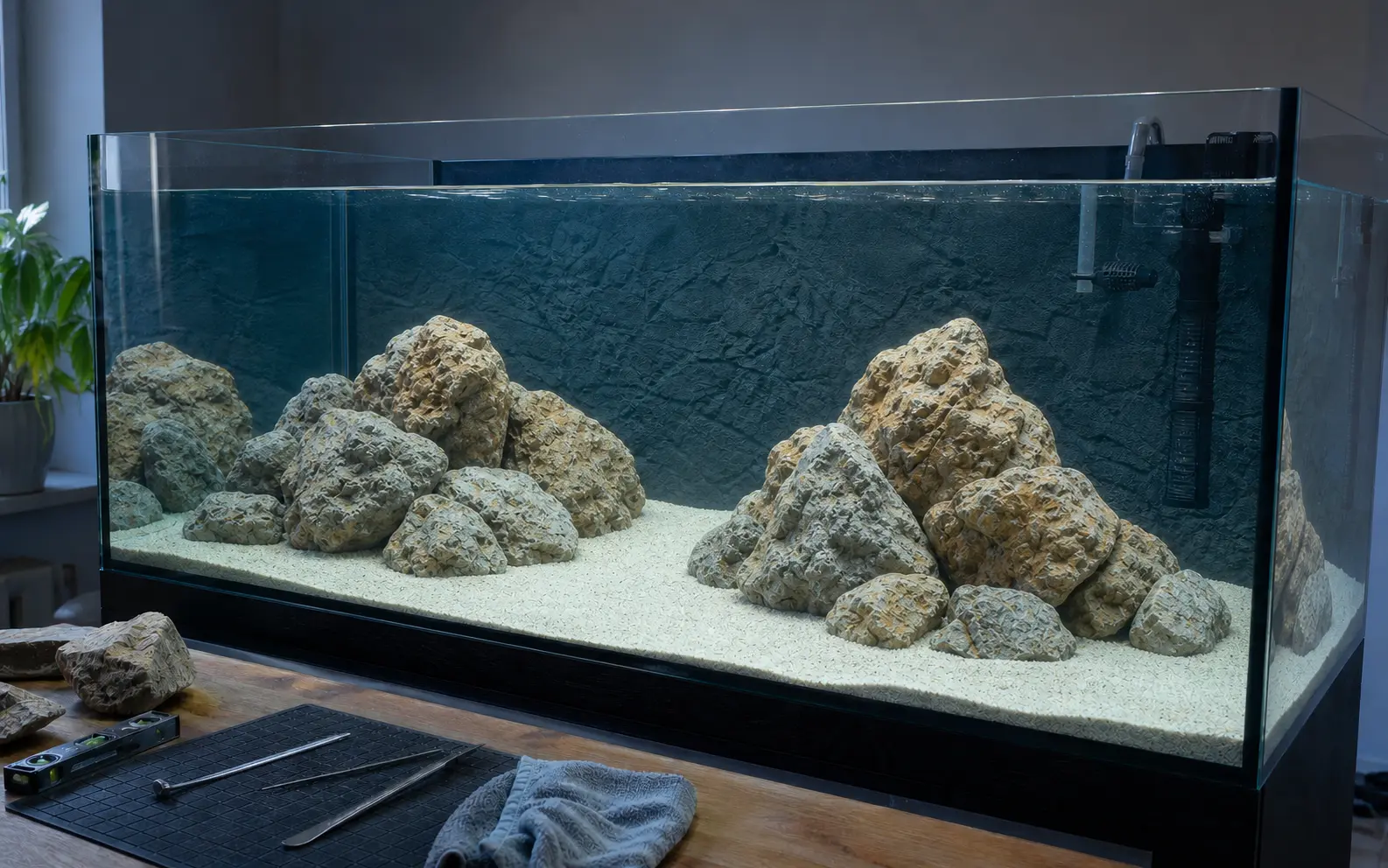 Leeres Malawi-Aquarium mit trocken geplanten Felsgruppen, freien Schwimmkorridoren und Messwerkzeugen vor dem Becken